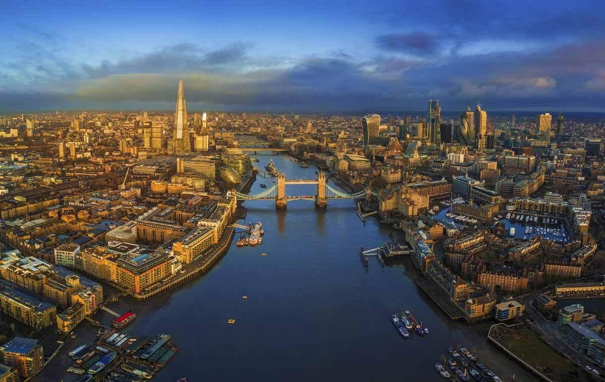London, England - Panoramic aerial skyline view of London including iconic Tower Bridge with red double-decker bus, Tower of London, skyscrapers of Bank District and other famous skyscrapers at golden hour early in the morning with colorful sky and clouds